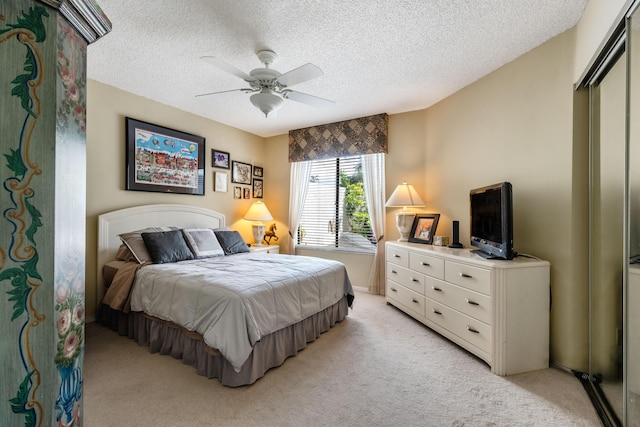 bedroom featuring a closet, ceiling fan, light carpet, and a textured ceiling