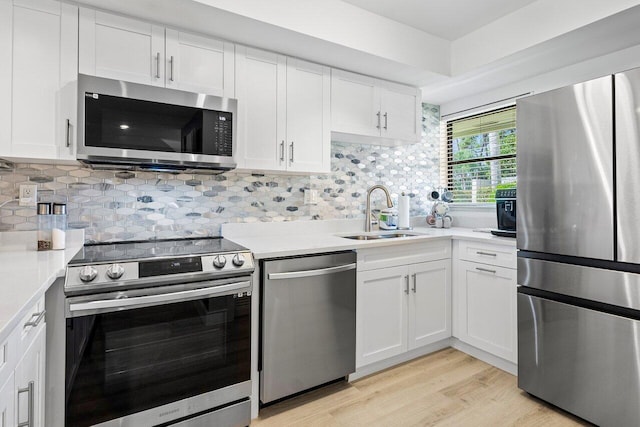 kitchen with stainless steel appliances, light wood-type flooring, sink, and white cabinetry