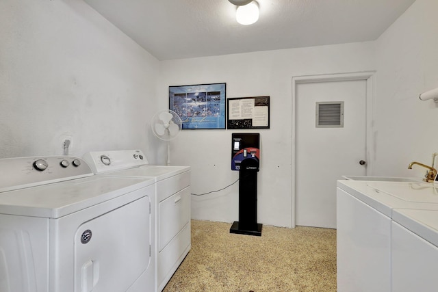 laundry room with a textured ceiling, washer and clothes dryer, and sink