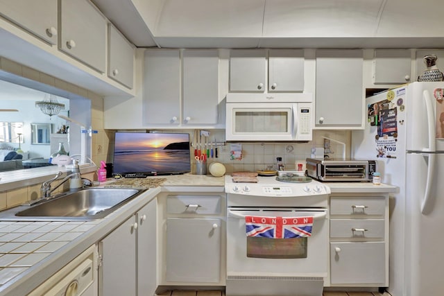 kitchen with a chandelier, tasteful backsplash, sink, white cabinets, and white appliances