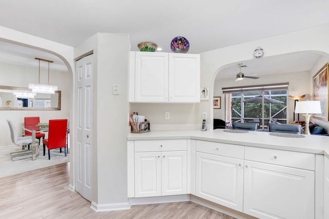 kitchen with white cabinets, decorative light fixtures, light hardwood / wood-style floors, and ceiling fan