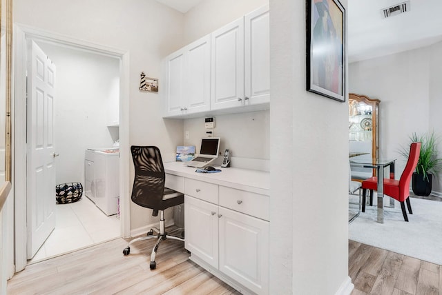 office with built in desk, washer / clothes dryer, and light hardwood / wood-style flooring