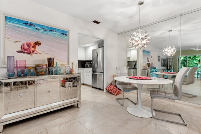 kitchen featuring hanging light fixtures, stainless steel fridge, a notable chandelier, and white cabinetry