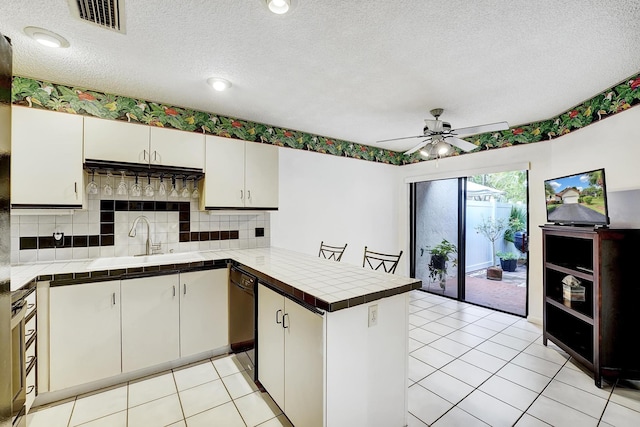 kitchen featuring sink, kitchen peninsula, ceiling fan, tile counters, and white cabinets