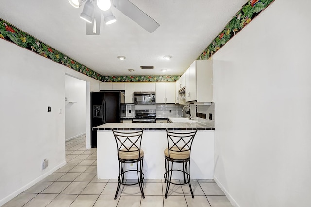 kitchen with kitchen peninsula, white cabinets, appliances with stainless steel finishes, a kitchen breakfast bar, and sink