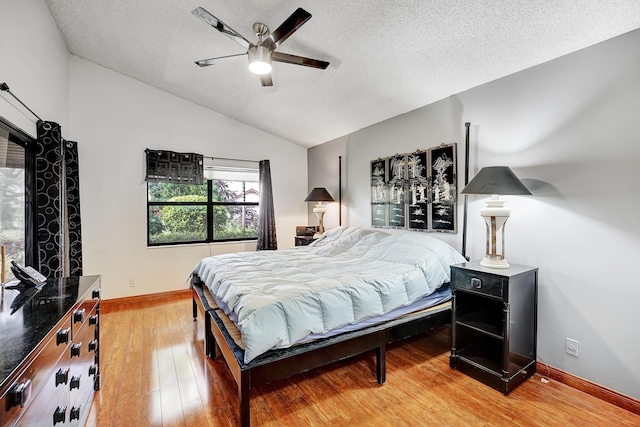 bedroom with ceiling fan, hardwood / wood-style flooring, a textured ceiling, and lofted ceiling