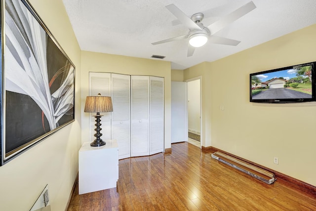 bedroom featuring a textured ceiling, hardwood / wood-style flooring, a closet, and ceiling fan