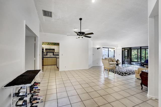 tiled living room featuring sink, ceiling fan, a textured ceiling, and lofted ceiling