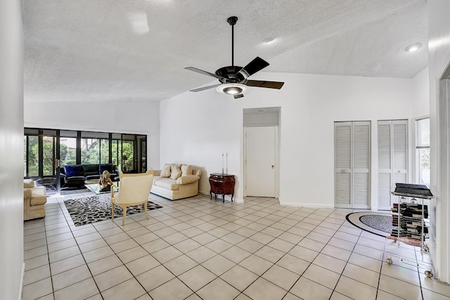 unfurnished living room with ceiling fan, high vaulted ceiling, a textured ceiling, and light tile patterned flooring