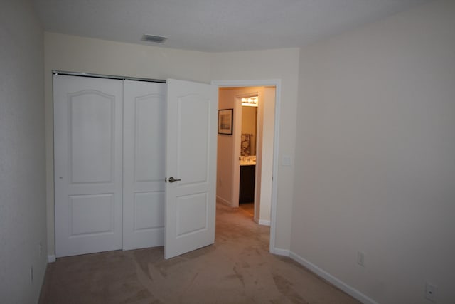 unfurnished bedroom with light colored carpet and a closet