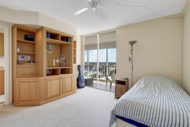 bedroom with a textured ceiling, light carpet, ceiling fan, and access to exterior