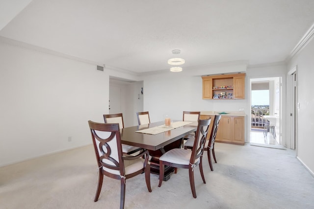 dining area with crown molding and light colored carpet