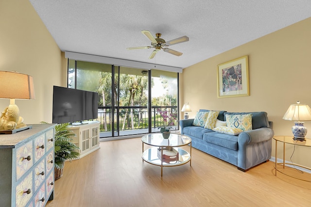 living area with floor to ceiling windows, a ceiling fan, wood finished floors, and a textured ceiling