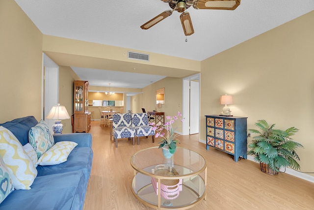 living room with a textured ceiling, light hardwood / wood-style floors, and ceiling fan