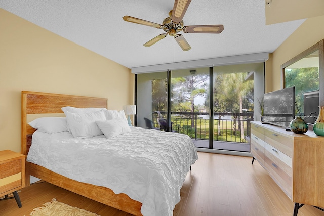 bedroom featuring access to outside, light wood-type flooring, multiple windows, a textured ceiling, and a ceiling fan