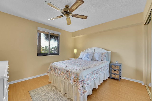 bedroom featuring ceiling fan, hardwood / wood-style flooring, and a textured ceiling