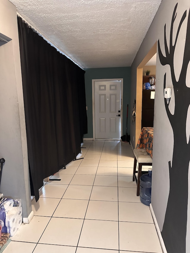 hallway with a textured ceiling and light tile patterned floors