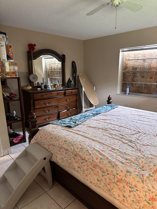 bedroom with a textured ceiling, light tile patterned floors, and ceiling fan