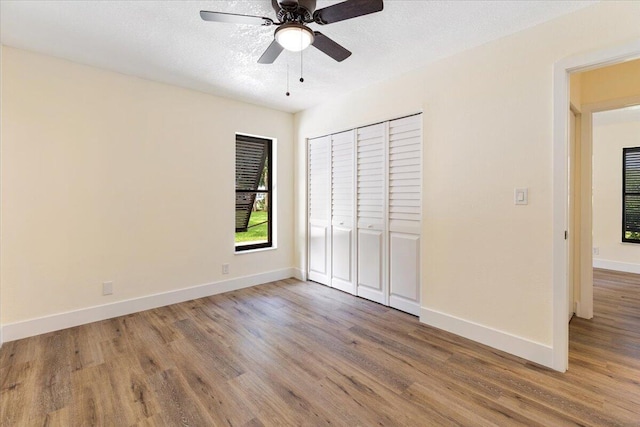 unfurnished bedroom featuring ceiling fan, a closet, and hardwood / wood-style flooring