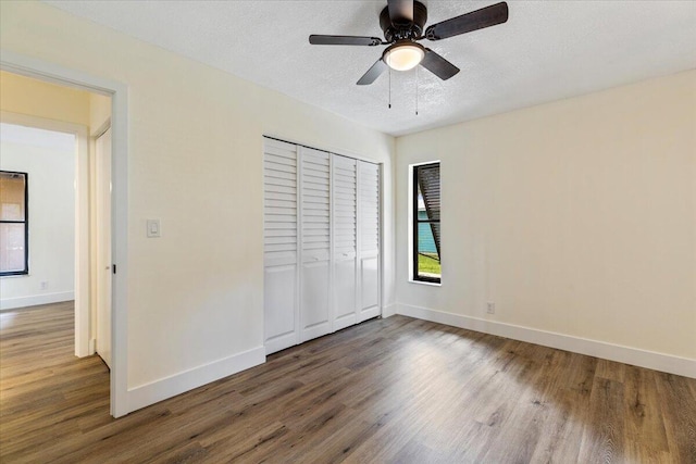 unfurnished bedroom with a textured ceiling, a closet, dark hardwood / wood-style floors, and ceiling fan