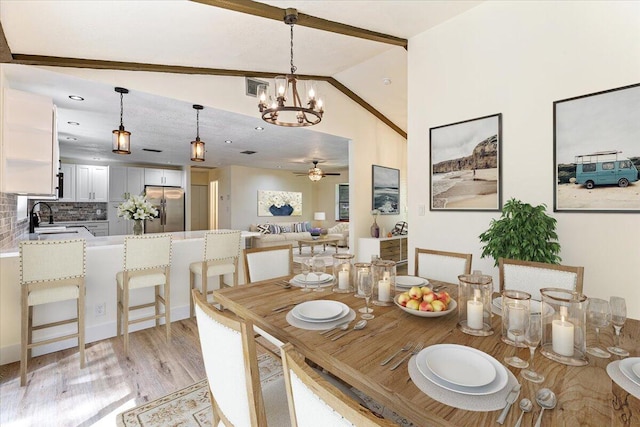 dining space with ceiling fan with notable chandelier, light hardwood / wood-style floors, lofted ceiling, and sink