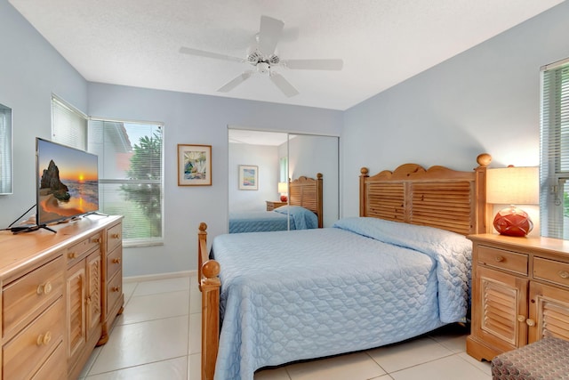 bedroom with a textured ceiling, light tile patterned floors, ceiling fan, and a closet