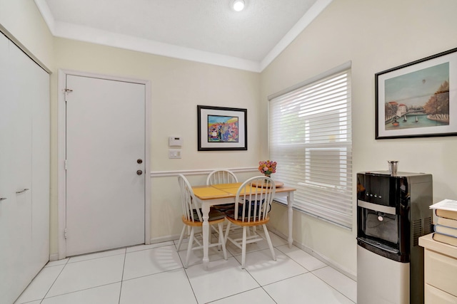 tiled dining space with ornamental molding and vaulted ceiling