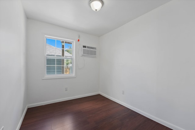 spare room with dark hardwood / wood-style flooring and an AC wall unit