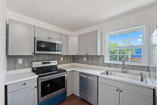 kitchen with gray cabinets, sink, decorative backsplash, stainless steel appliances, and dark hardwood / wood-style flooring