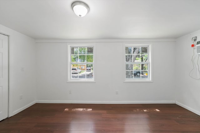 spare room with a healthy amount of sunlight and dark wood-type flooring