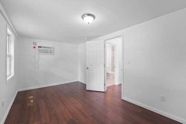 unfurnished room with a wall unit AC and dark wood-type flooring