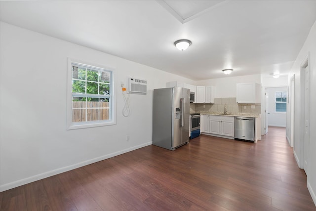 kitchen with white cabinets, appliances with stainless steel finishes, dark hardwood / wood-style flooring, and tasteful backsplash