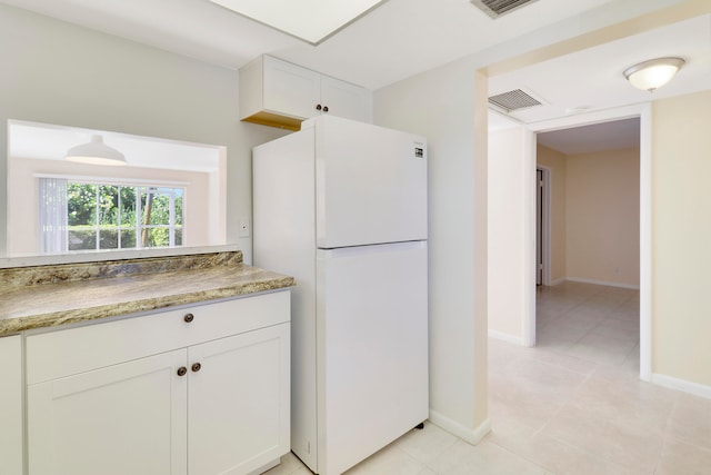 kitchen featuring white cabinetry, light stone counters, and white fridge