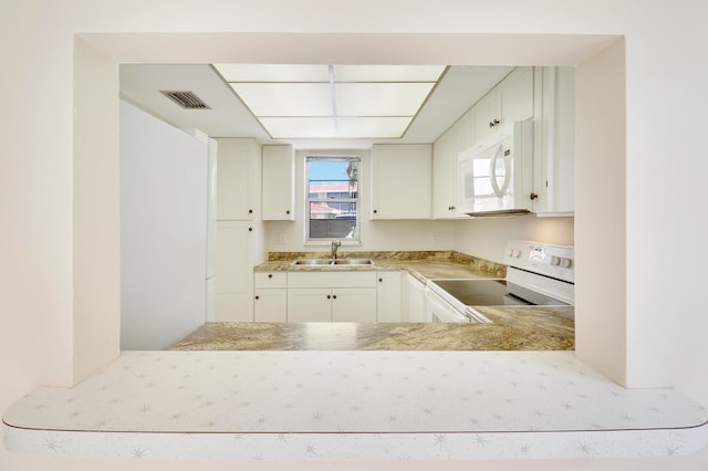 kitchen featuring sink, white appliances, and white cabinetry