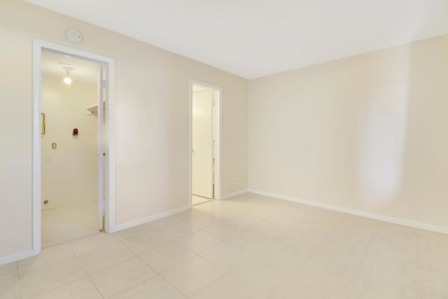 unfurnished bedroom featuring a spacious closet, light tile patterned floors, and a closet