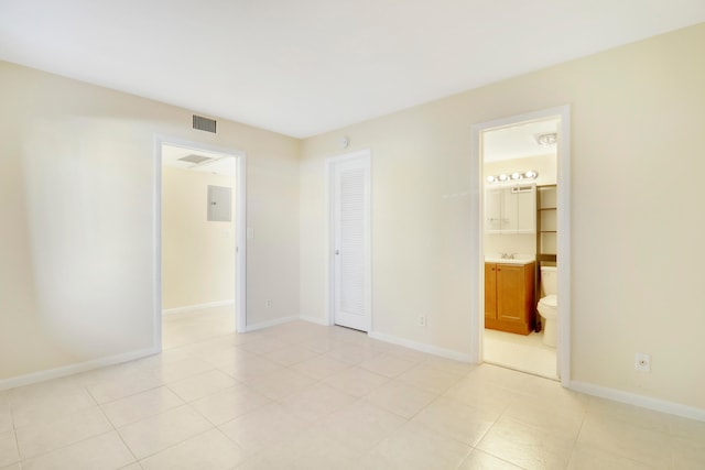 unfurnished bedroom featuring sink, light tile patterned floors, ensuite bathroom, and a closet