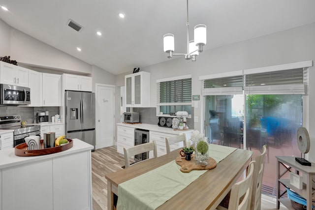 kitchen with wine cooler, appliances with stainless steel finishes, decorative light fixtures, and white cabinets