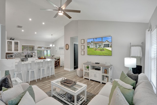 living room featuring ceiling fan, high vaulted ceiling, and light hardwood / wood-style floors