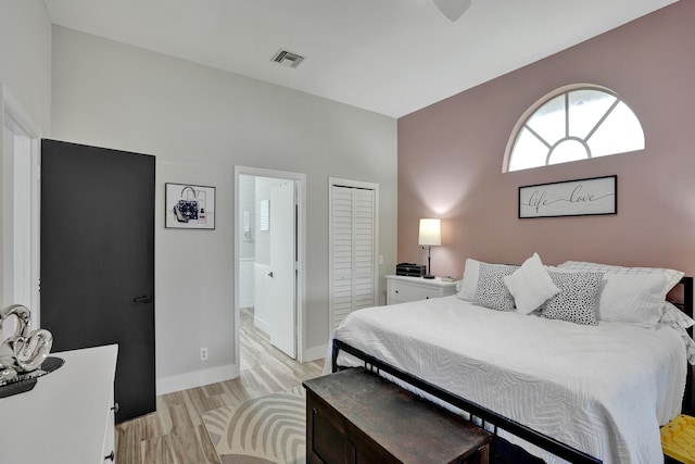 bedroom with ensuite bathroom, light wood-type flooring, and a closet