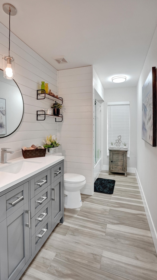 full bathroom with vanity, shower / bath combination with glass door, and toilet