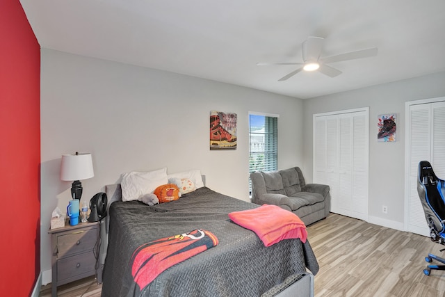 bedroom featuring two closets, light hardwood / wood-style floors, and ceiling fan