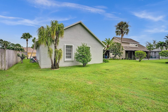 exterior space featuring fence, a yard, and stucco siding
