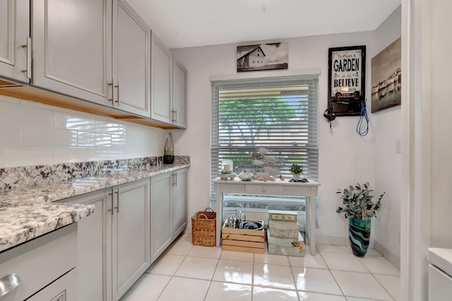 kitchen with decorative backsplash, light stone countertops, and light tile patterned floors