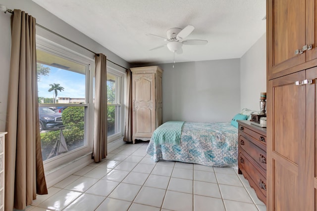 bedroom with a textured ceiling, light tile patterned flooring, and ceiling fan