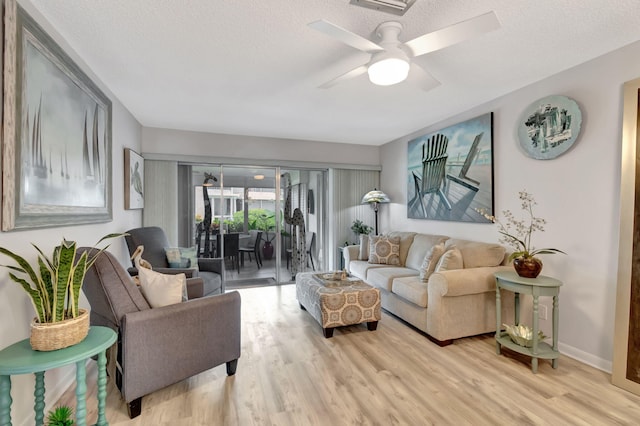 living room featuring light hardwood / wood-style flooring, ceiling fan, and a textured ceiling