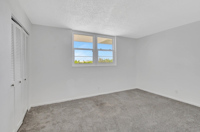 unfurnished bedroom with a textured ceiling, two closets, and light colored carpet