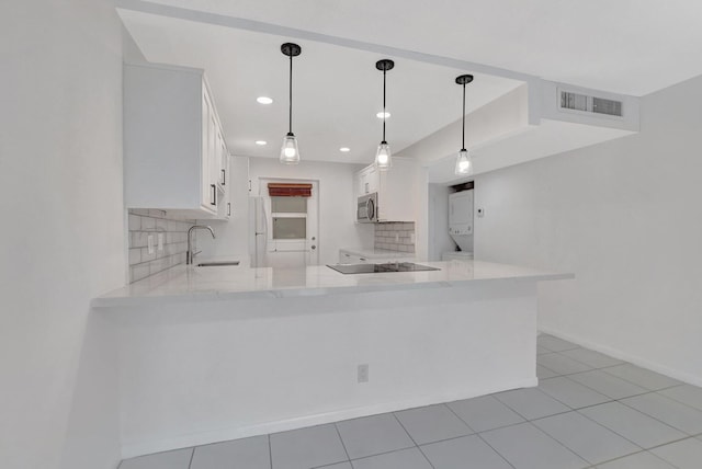 kitchen featuring kitchen peninsula, decorative backsplash, hanging light fixtures, white cabinetry, and sink