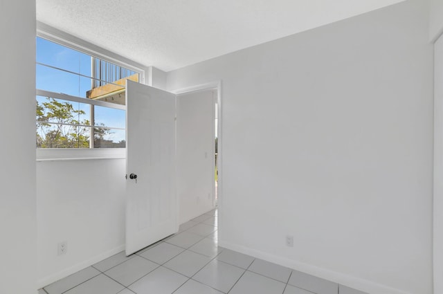 spare room with a textured ceiling and light tile patterned floors