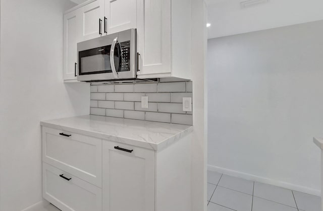 kitchen with white cabinetry, light stone counters, and light tile patterned floors