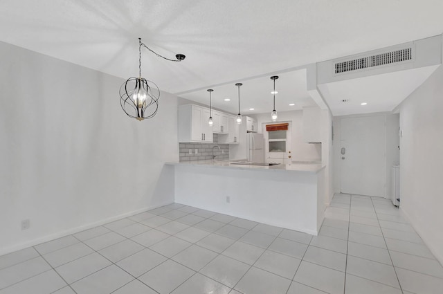 kitchen with tasteful backsplash, sink, kitchen peninsula, hanging light fixtures, and white cabinetry